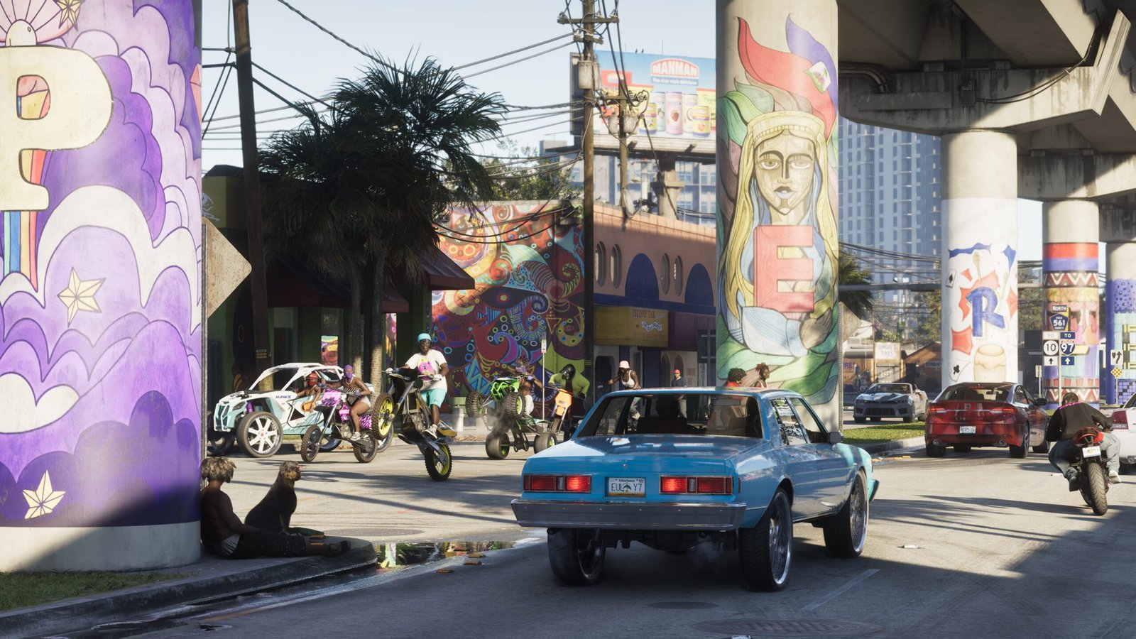 Escena callejera de Vice City en GTA 6 con un coche clásico azul, motos y quads circulando bajo una autopista con murales de colores, imagen oficial de Rockstar Games